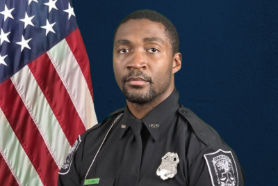 Officer David Rose in uniform by the American flag